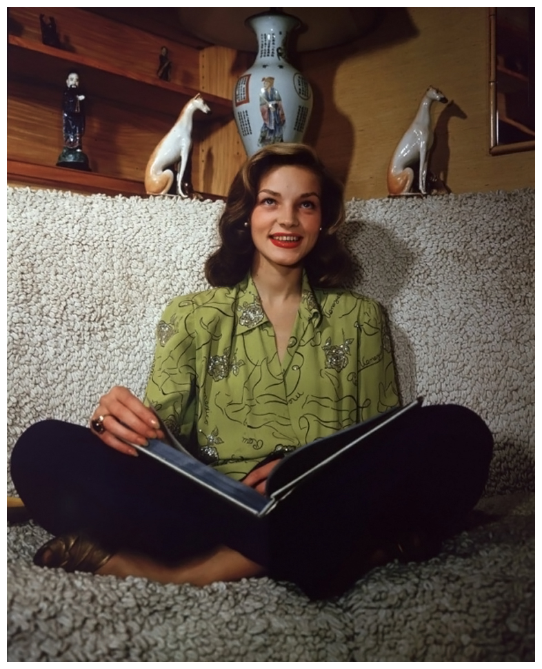1945-american-actor-lauren-bacall-smiling-and-sitting-cross-legged-on-a-sofa-an-open-book-in-her-lap-photo-by-hulton-archivegetty-images