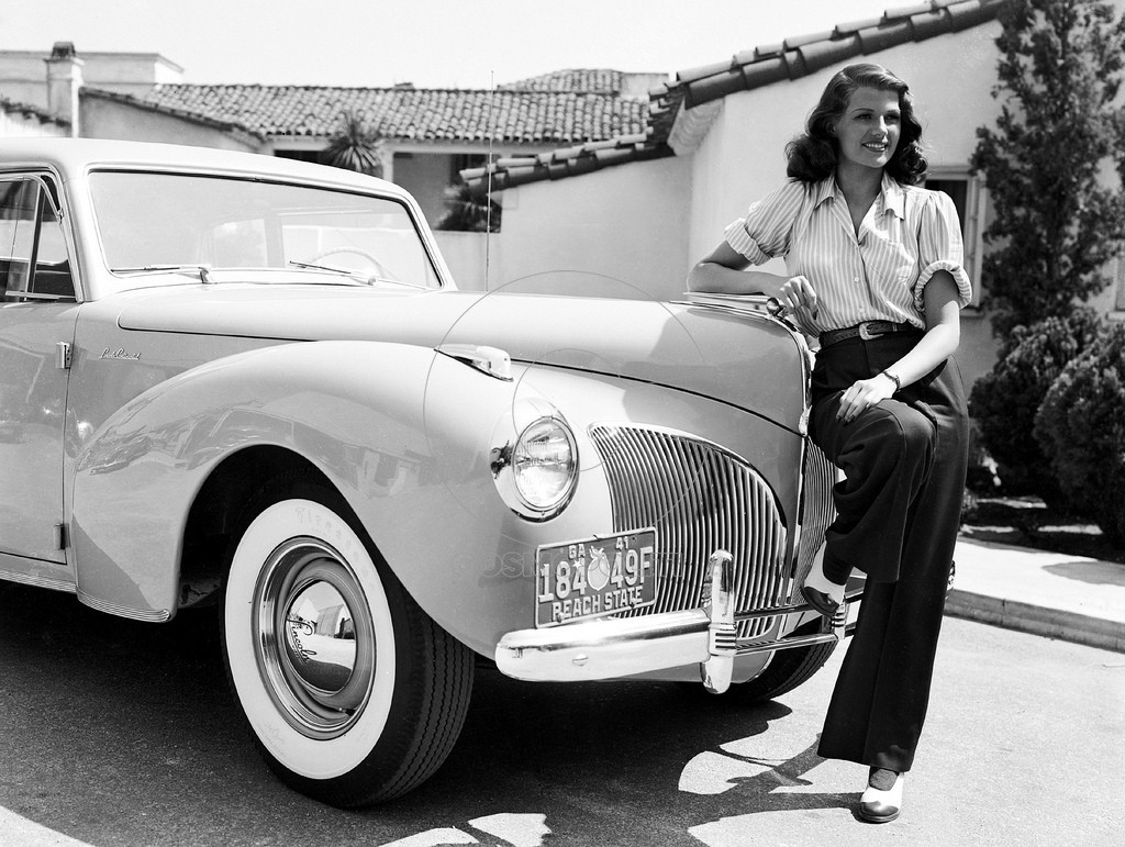 1941: American screen beauty Rita Hayworth (1918 - 1987) poses beside an automobile.